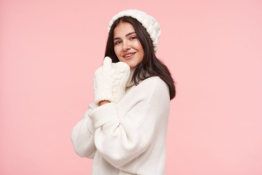 indoor shot young pretty brunette woman with natural makeup folding raised hands near her face smiling positively front isolated pink wall 1 scaled